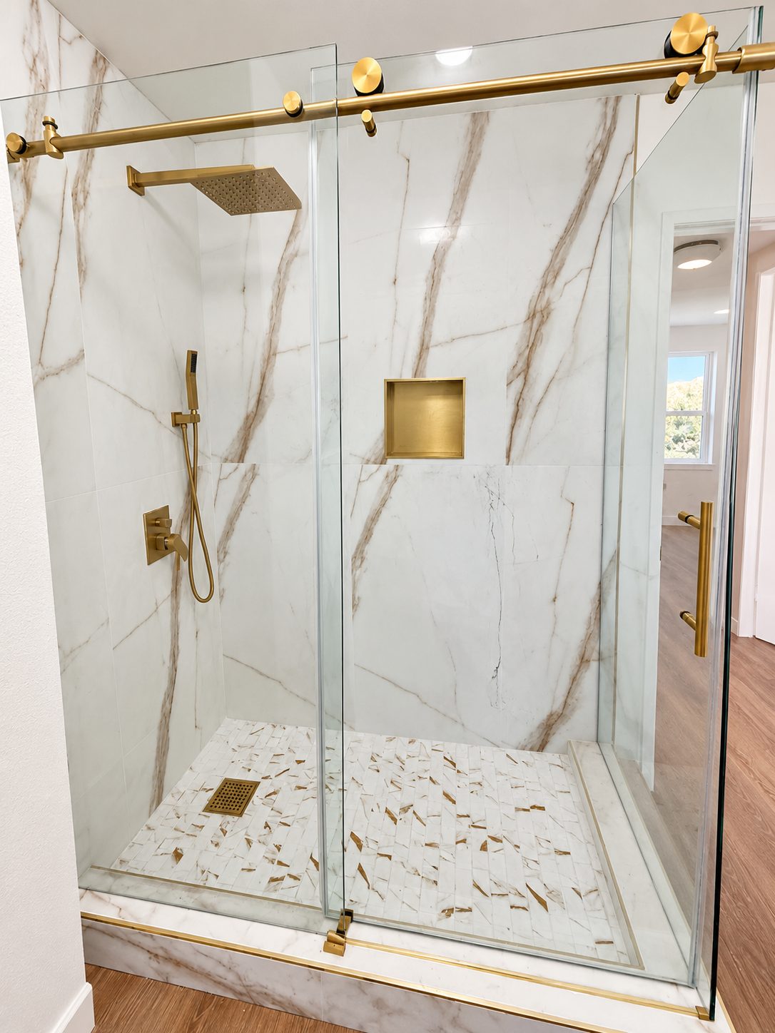 Calacatta gold shower with brass rain head and frameless sliding glass