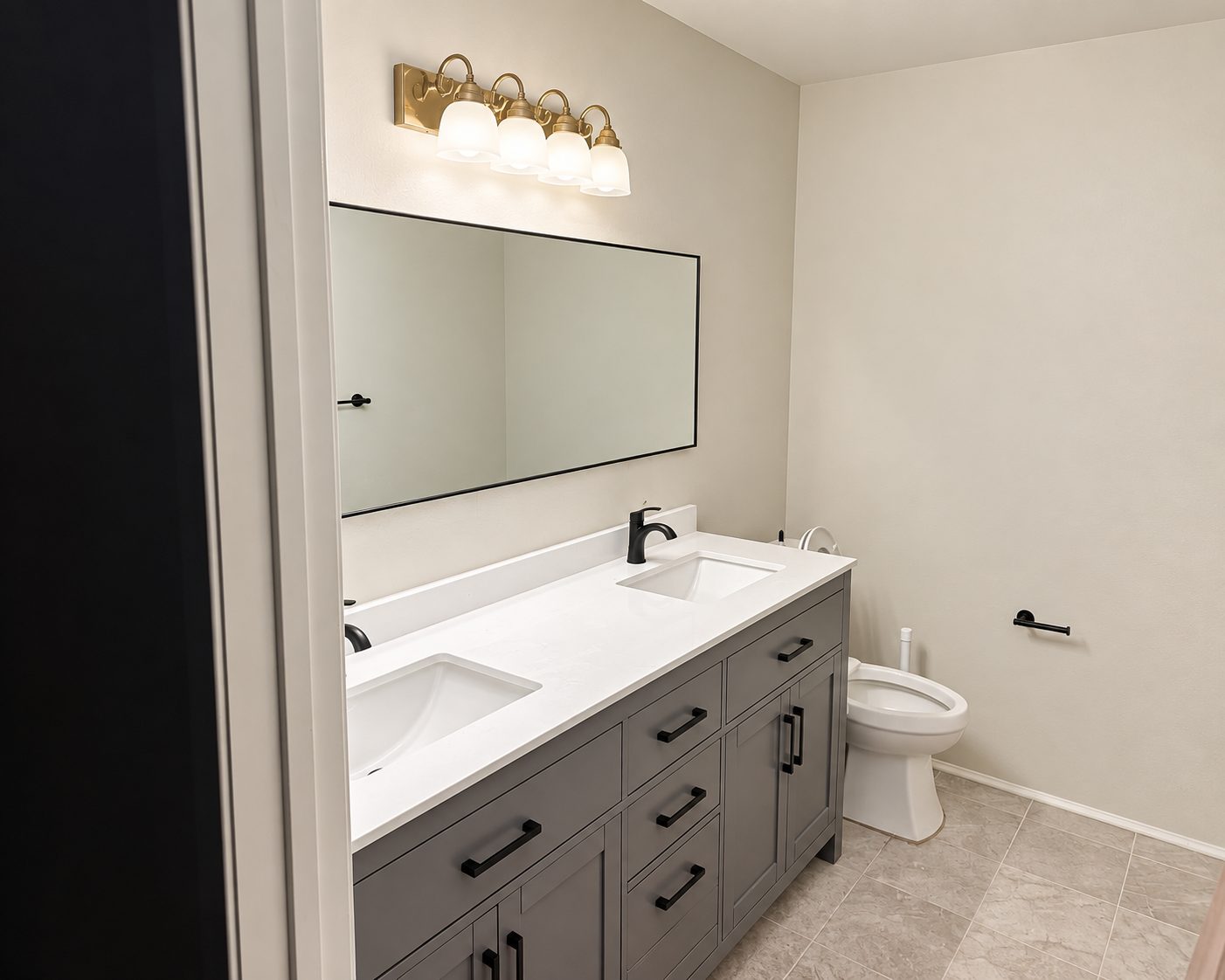 Double vanity with quartz top, black hardware and brass sconce