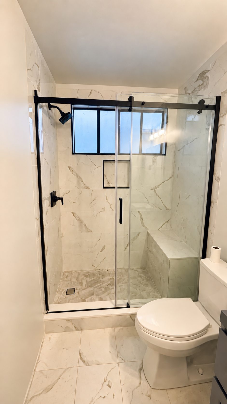 Completed walk-in shower with black-framed glass door
