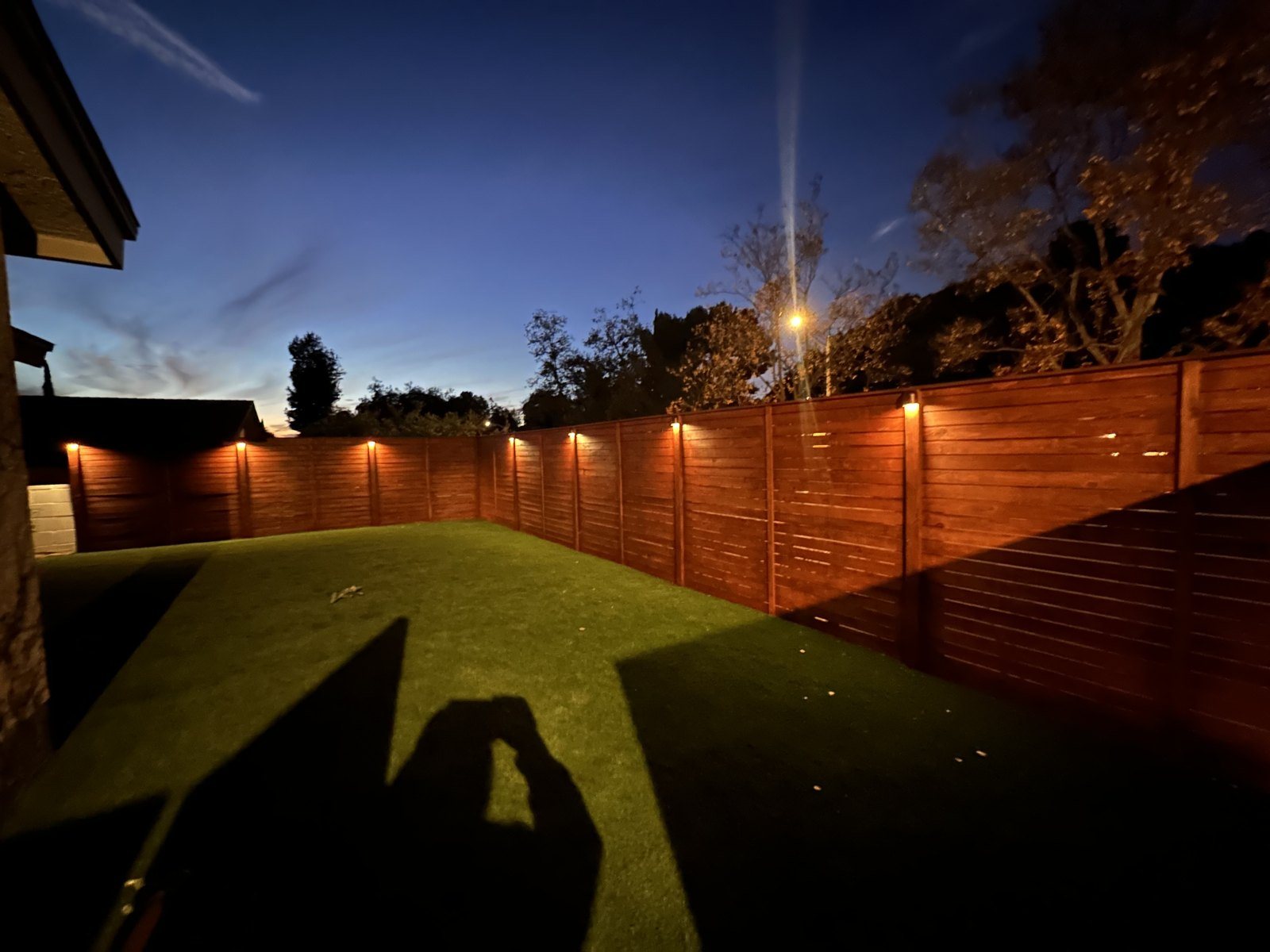 Redwood fence and backyard lit up at dusk, a WeFiks project
