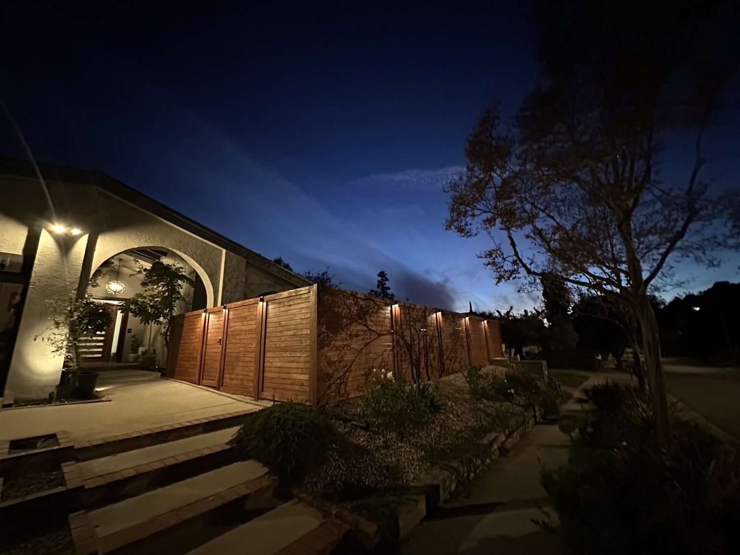 Redwood fence and entry lit up at dusk