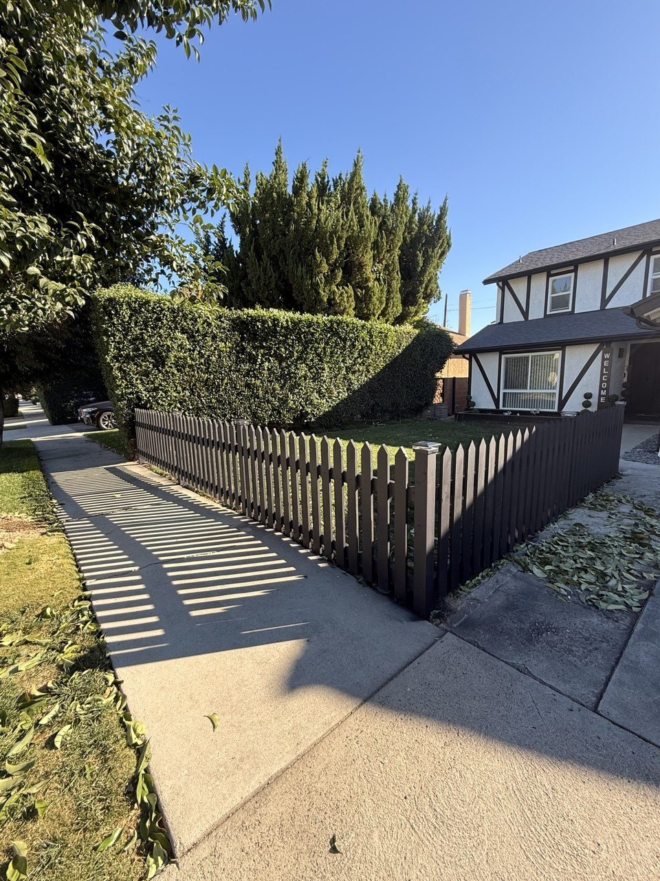 Black stained picket fence along a front lawn