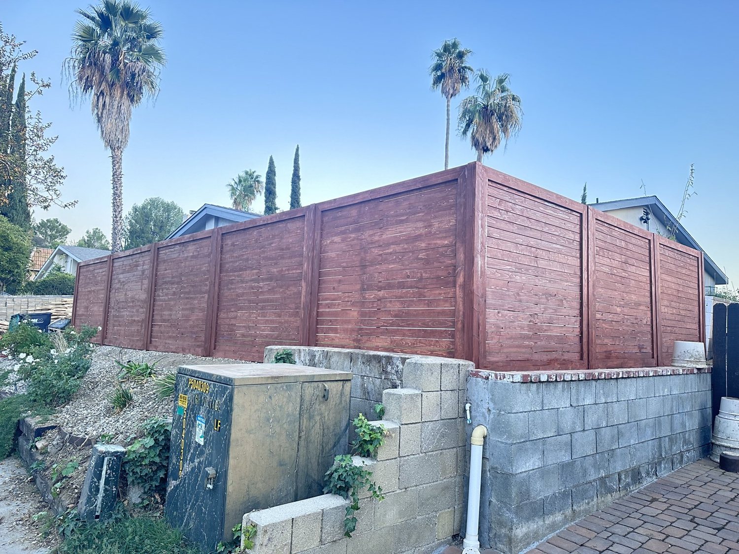 Stained horizontal fence on top of a block wall
