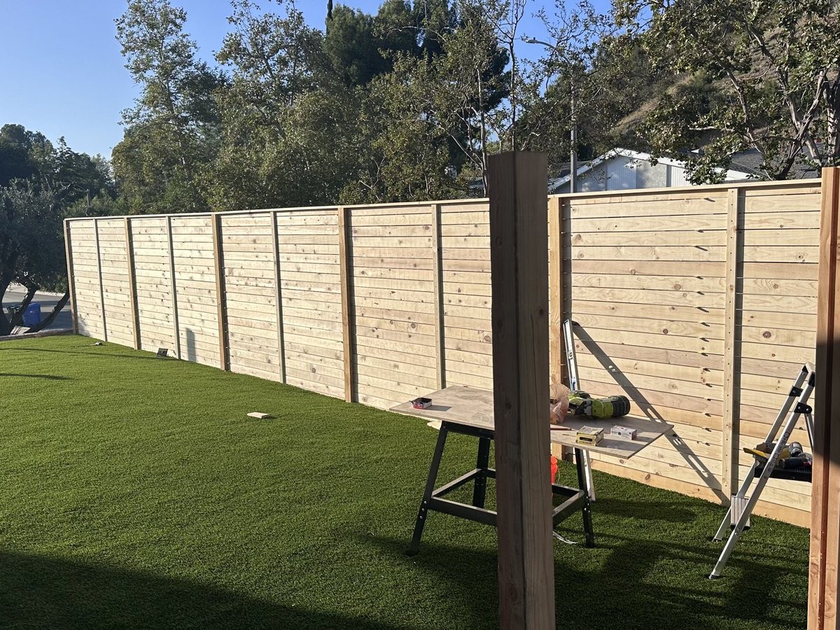 Horizontal cedar boards going onto the rails, screwed one by one