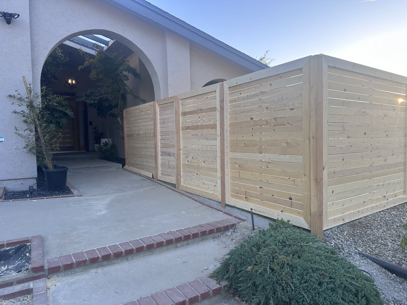 Finished horizontal cedar fence and gate at the entry, natural wood