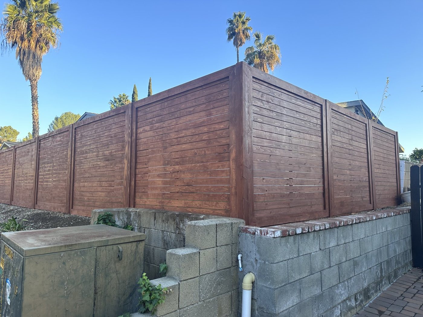 The same fence after three coats of redwood stain