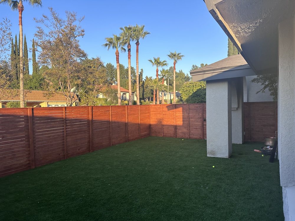 Stained horizontal redwood fence around a lawn